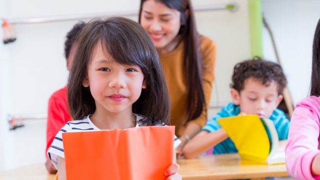 Girl with book in front of teacher